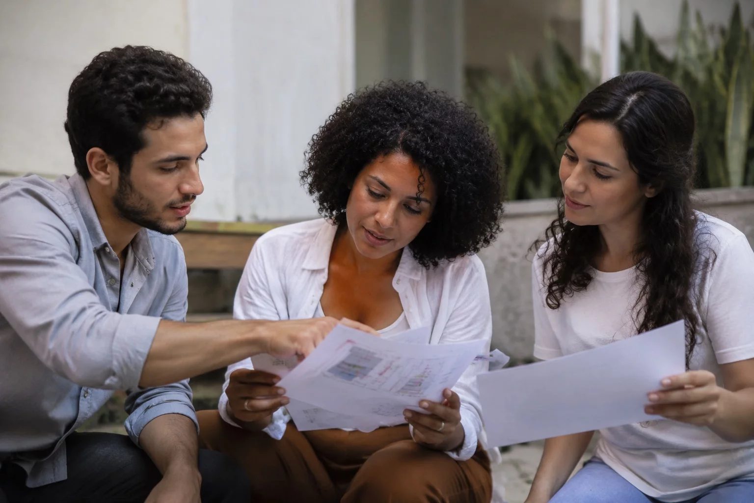 Grupo pequeno lendo páginas impressas de argumentos ao redor de uma mesa
